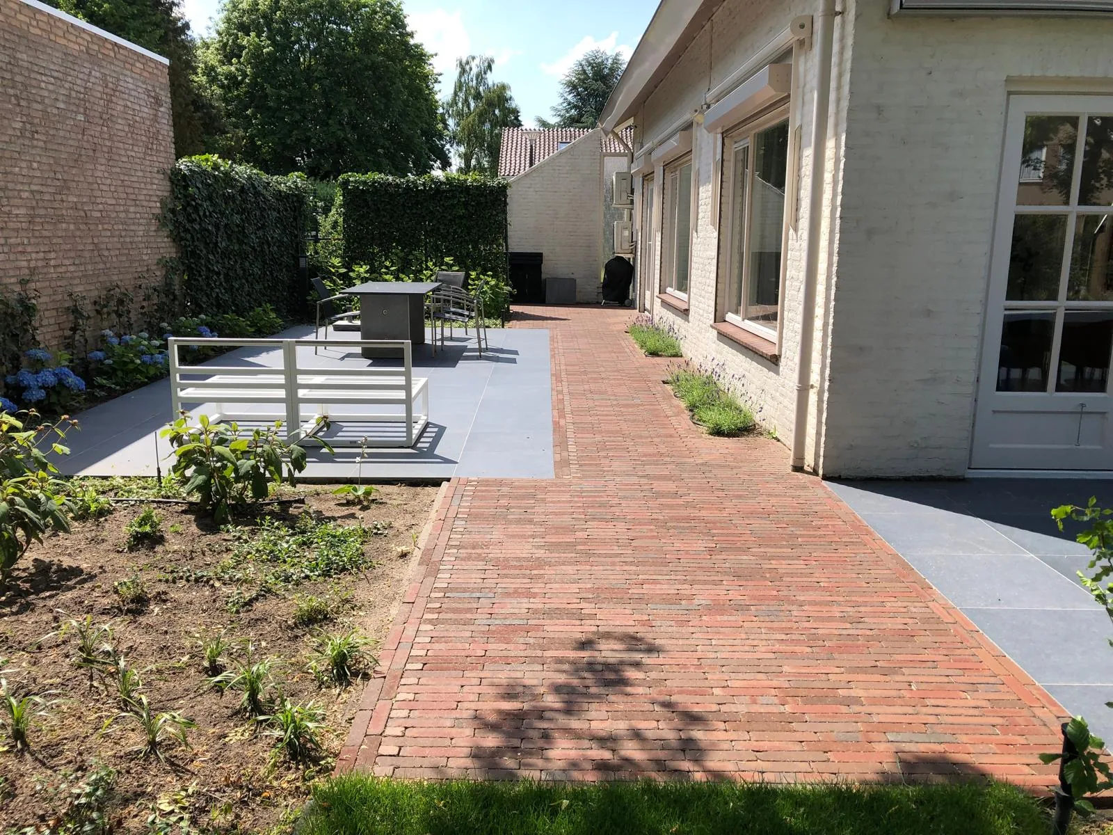 Tuinpad in rode klinkers langs de woning met keramisch terras