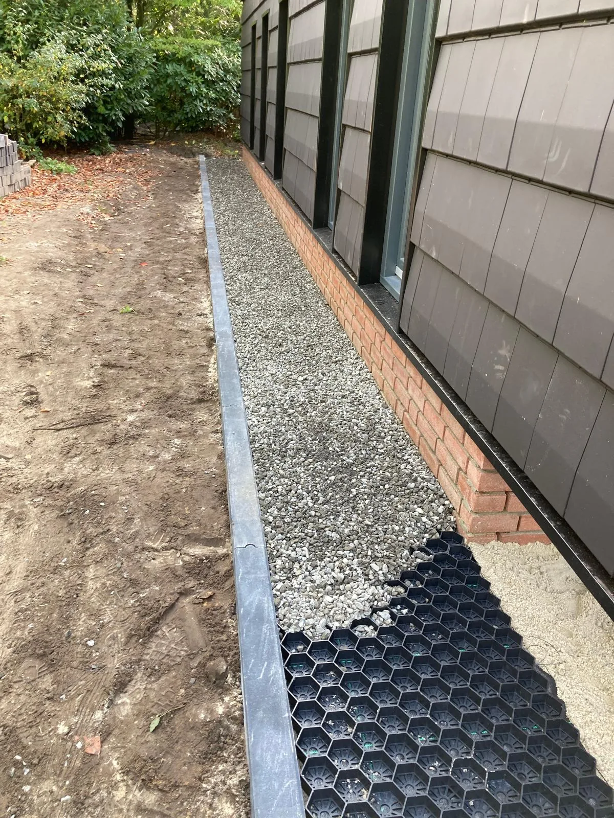 Grindkoffer met opsluitband en grasbetontegels langs de gevel voor goede waterafvoer