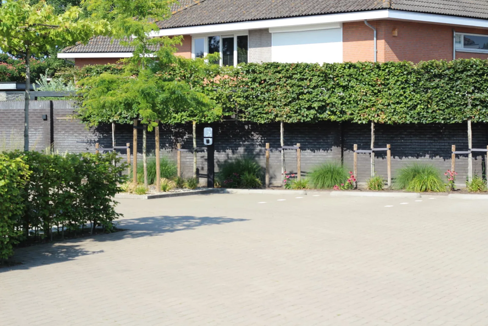 Parkeerterrein in lichte betonklinkers met parkeervakken, opsluitbanden en borders