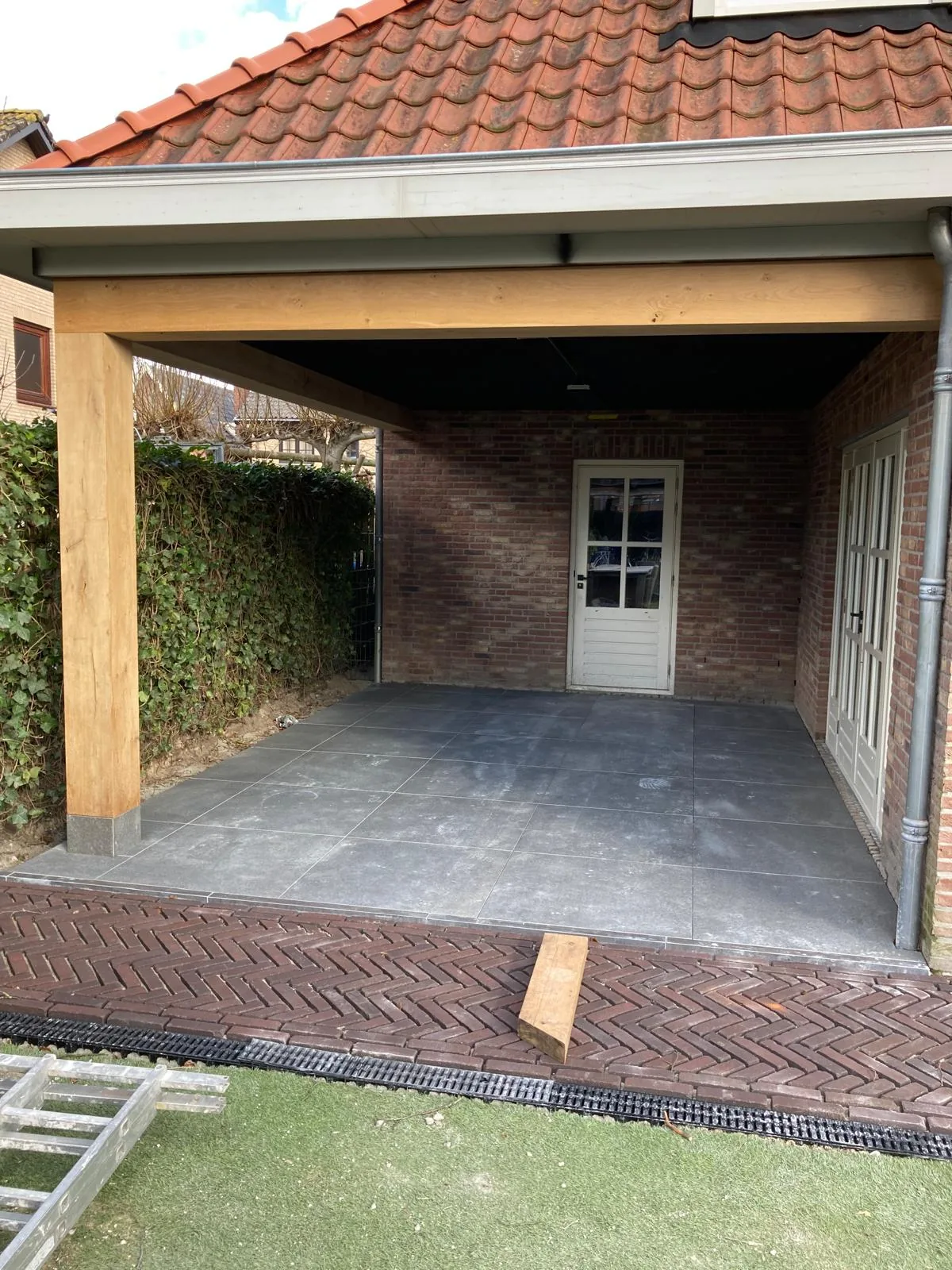 Keramisch terras onder een houten overkapping met een rand in gebakken klinkers