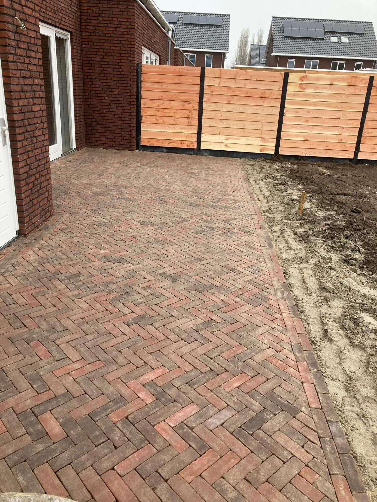 Terras in gebakken klinkers in visgraatverband langs de woning