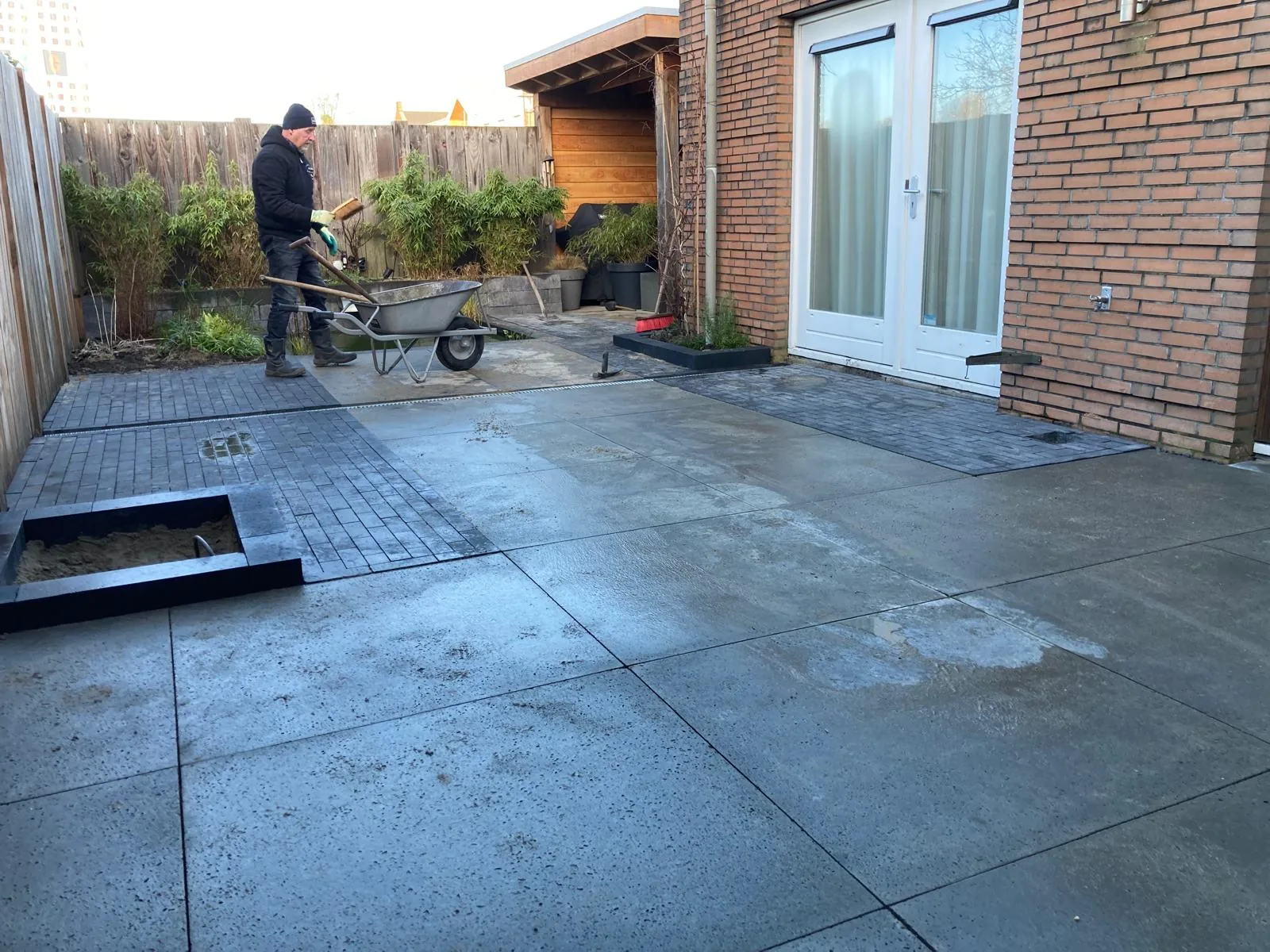 Terras in grootformaat betontegels in aanleg met een strook gebakken klinkers