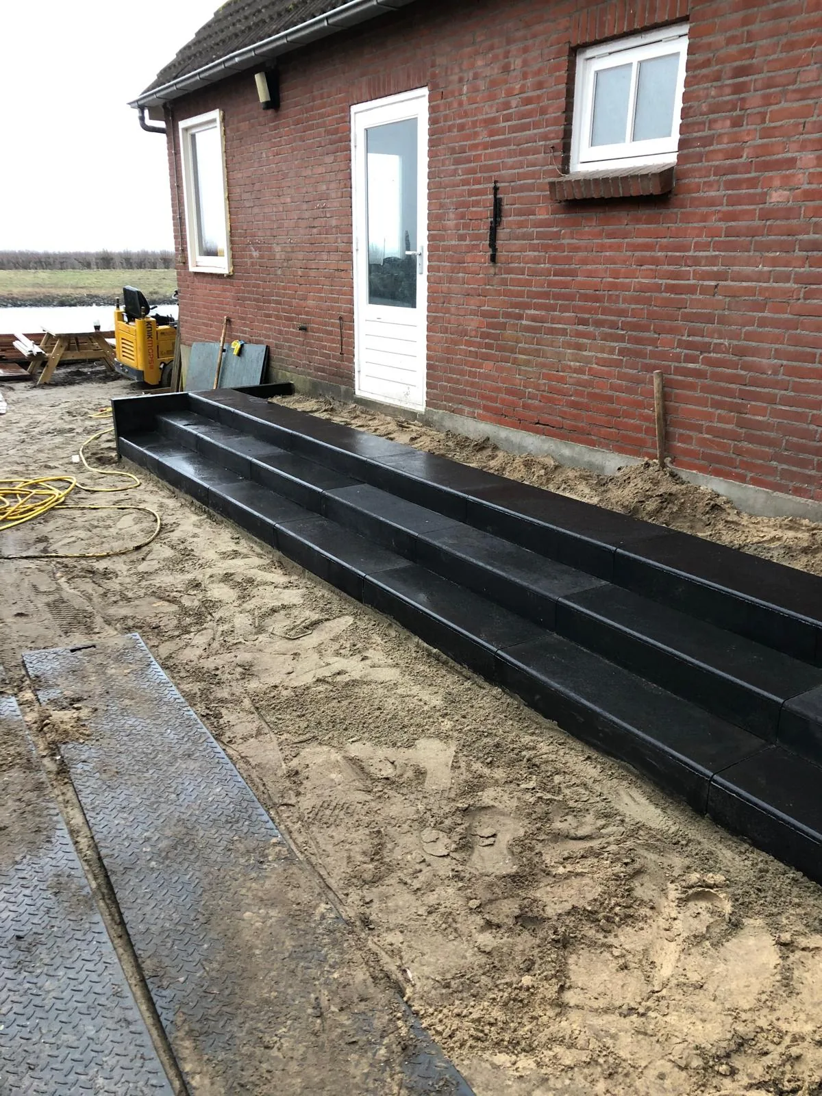Aangelegde traptreden en terrasrand in zwarte banden tijdens het grondwerk