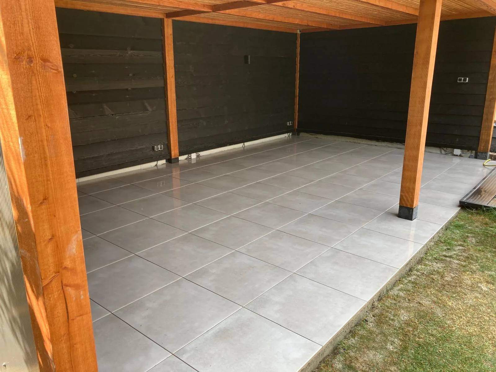 Keramische vloer in een houten veranda met zwarte wanden