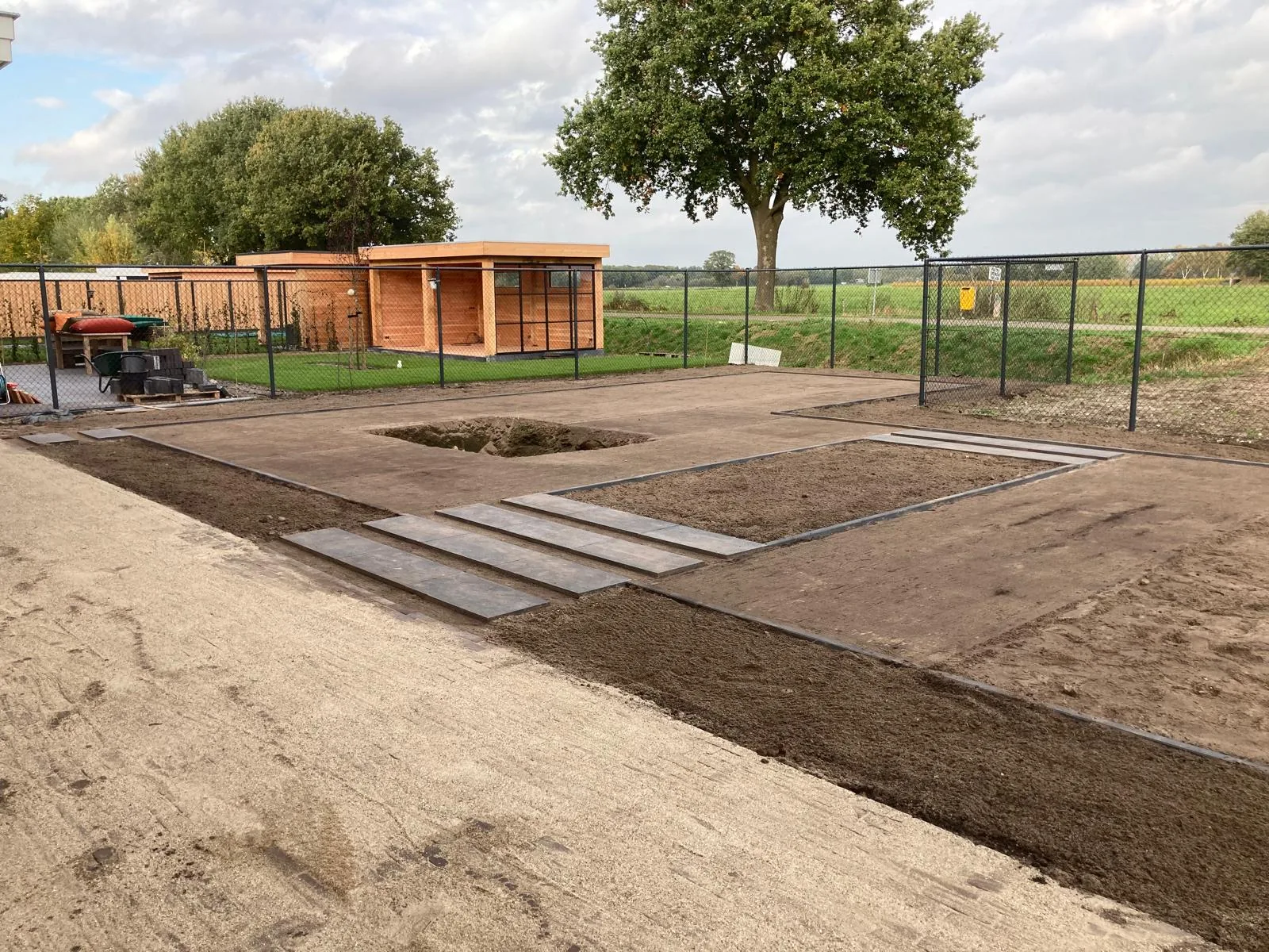 Grondwerk voor een nieuwe tuin met uitgezette borders en een keramisch pad