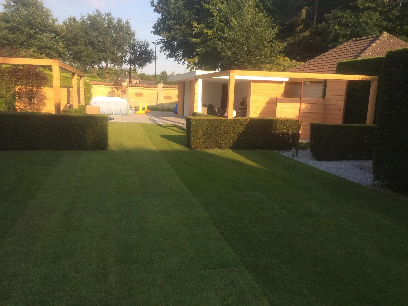 Complete tuinaanleg met verse graszoden, hagen en houten overkapping