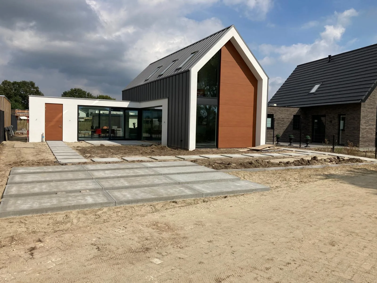 Oprit en pad in grote betonplaten bij een nieuwbouwwoning met zwarte gevel