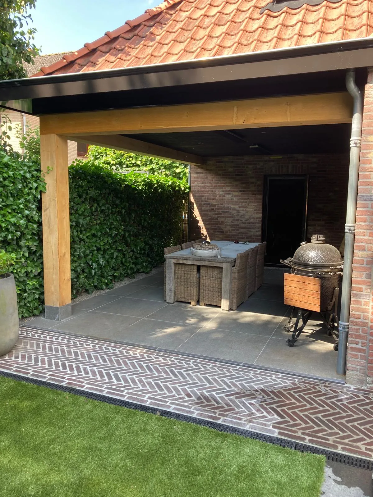 Overkapt terras met buitenkeuken, keramische tegels en gebakken klinkers in visgraatverband