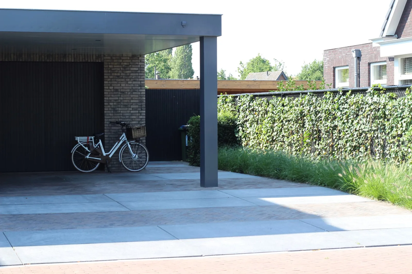 Carport en oprit in grootformaat tegels met stroken gebakken klinkers